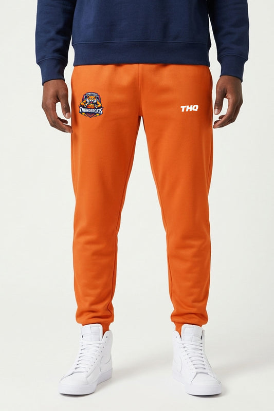 Athlete wearing orange performance bottoms with THQ logo and Thundercats logo. 